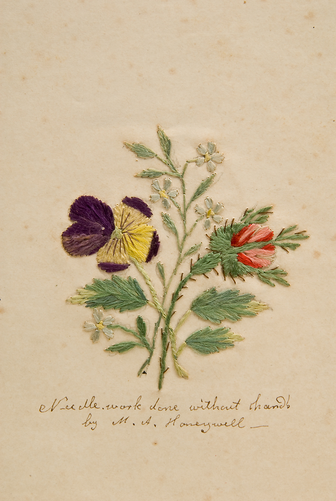 Needlework - flowers, purple, yellow, and red. Signature says "Needlework done without hands by M.A. Honeywell."